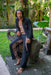 Man sitting on a stone bench outdoors with greenery in the background