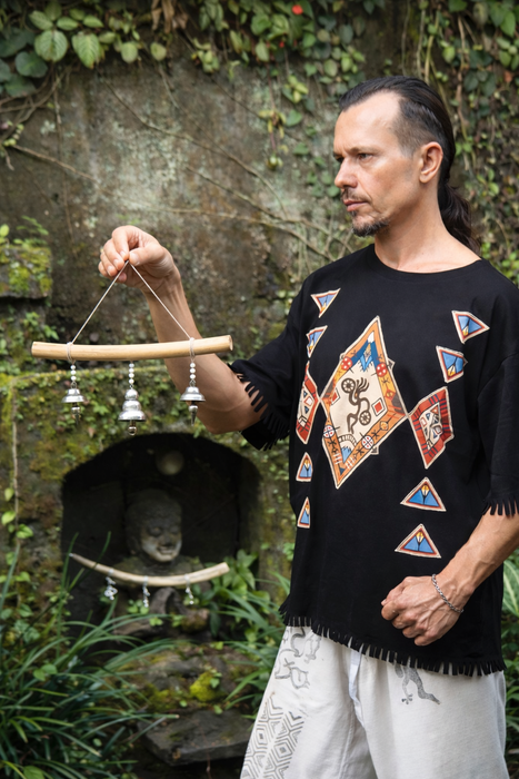 Man holding a wind chime in a natural setting with greenery.