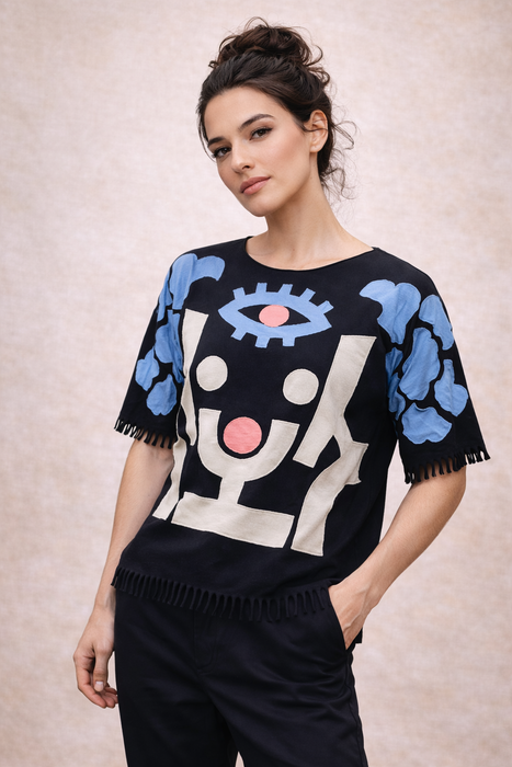 Woman wearing a black sweater with abstract designs on a beige background