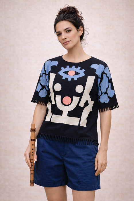 Woman wearing a black sweater with abstract designs and blue shorts on a beige background