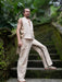 Man in beige vest and pants standing on a mossy staircase with greenery in the background