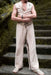 Person wearing a sleeveless top and wide-leg pants with decorative elements on a stone staircase.