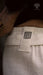 Close-up of a beige fabric with a black spiral pattern tag, worn by a person.