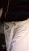 Close-up of a person wearing white pants with a visible brand logo.