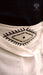 Close-up of a white garment with black geometric design, featuring the brand 'AYAHO'.