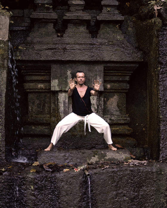 Person in martial arts pose in front of a stone structure