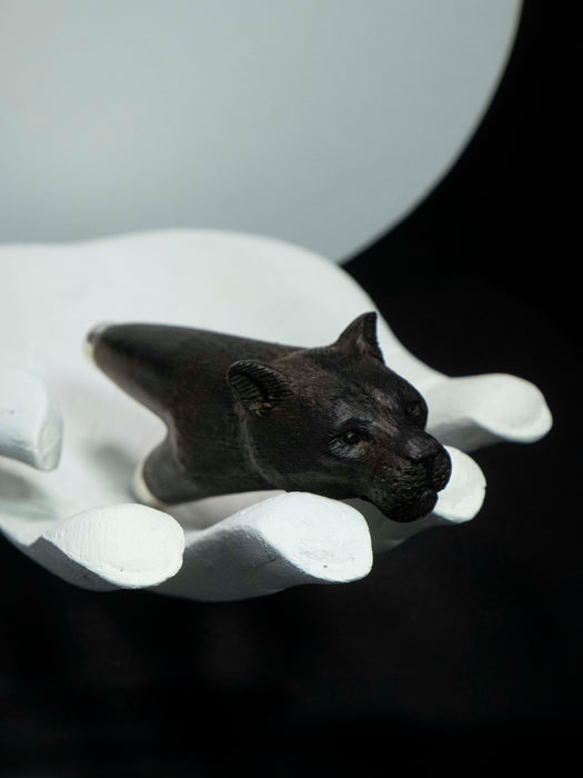 Black panther figurine on a white pedestal against a dark background
