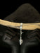 Silver bracelet with an arrowhead charm on a wooden stick against a dark background