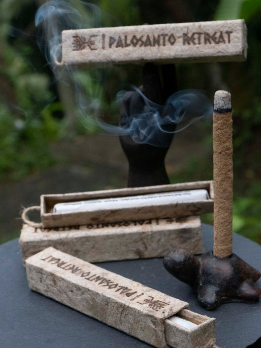 Palo Santo incense sticks with smoke and packaging on a dark surface