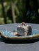 Incense stick burning on a ceramic plate with a blurred natural background