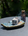 Ceramic dish with a rock and sand on a reflective surface