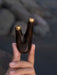Wooden object with gold tips held by a hand against a dark background