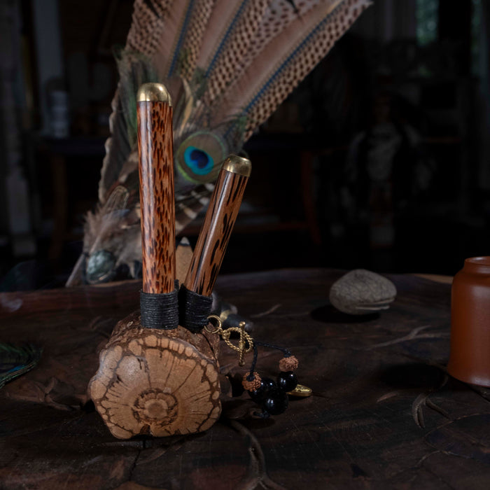 Wooden and metallic tools on a dark surface with peacock feathers in the background