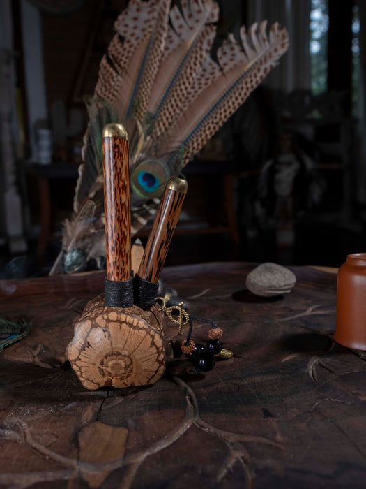 Wooden tool set with peacock feather and stone on a textured surface