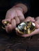 Close-up of hands holding a small brass tray with coins and a ring.
