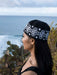 Woman wearing a black and white patterned beanie with ocean and cacti in the background