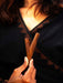 Person holding two wooden sticks with a dark background