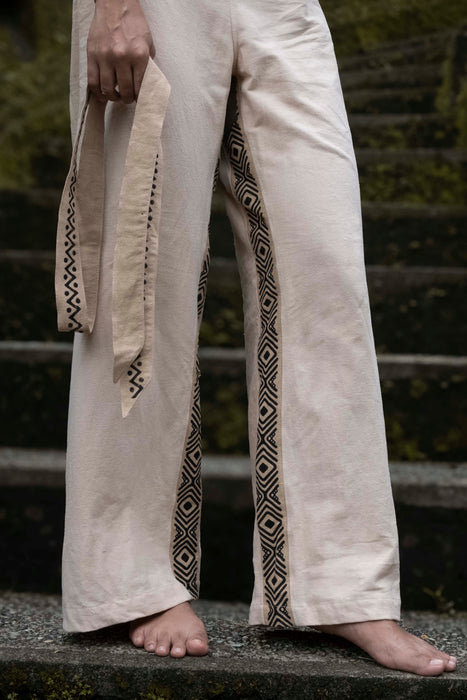 Person wearing light-colored pants with geometric patterns standing on steps.