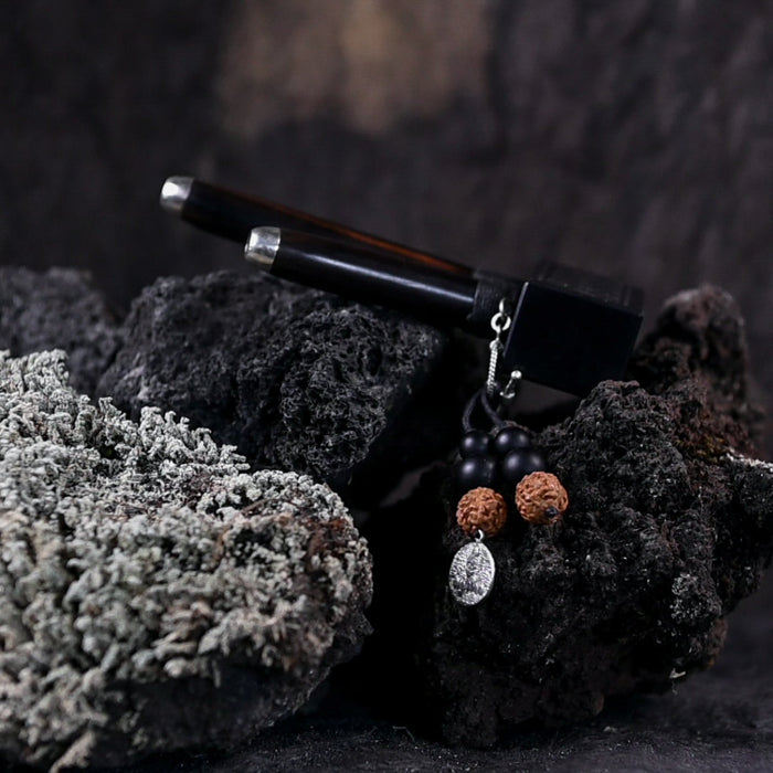 Black pen and earrings on a textured black surface with a blurred background