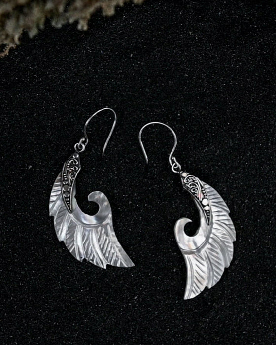 Exquisite Angel Wings earrings, crafted from lustrous mother-of-pearl and detailed sterling silver, radiating aesthetic grace and ethereal charm
