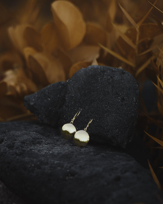 Matte bronze earrings with hammered textures and small mirrors, paired with terracotta jewelry.