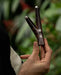 Elite rosewood kuripe pipe with intricate Shipibo patterns, held aloft, a sophisticated tool for hape snuff and a testament to shamanic craftsmanship.