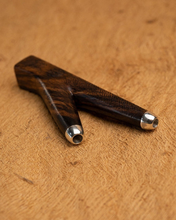 Elite rosewood kuripe pipe with intricate Shipibo patterns, held aloft, a sophisticated tool for hape snuff and a testament to shamanic craftsmanship.