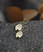Close-up of artisan-crafted bronze earrings with circular mirrors, showcasing intricate tribal engravings on textured metal