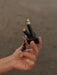 Hand holding a small black device with gold accents against a blurred background