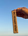 Hand holding a Palo Santorit stick against a clear blue sky