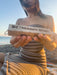 Person holding a Palo Santo retreat wooden block on a beach