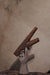 Wooden letter 'K' held by a stone hand against a beige background