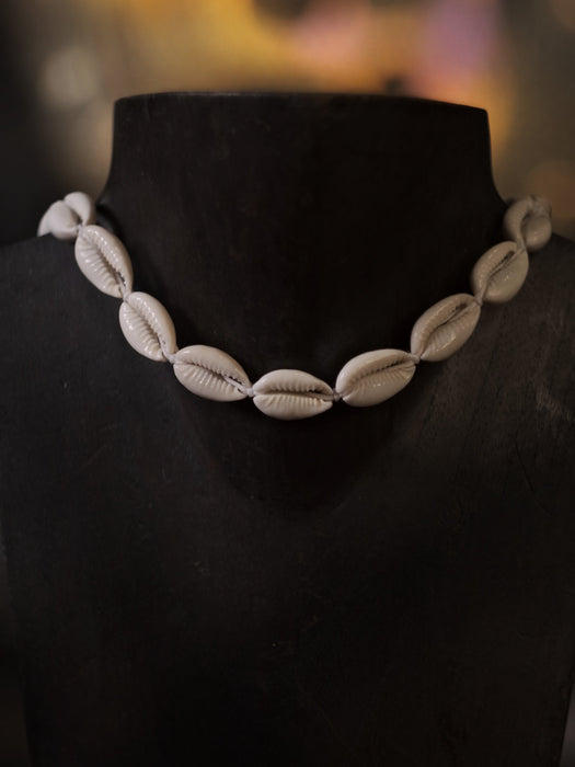 Necklace made of cowrie shells on a black mannequin with a blurred background