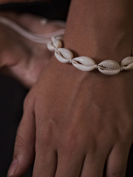 Close-up of a shell anklet on a person's ankle with a blurred background
