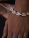 Close-up of a shell anklet on a person's ankle with a blurred background