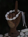 Bracelet made of cowrie shells on a wooden hand with a dark background
