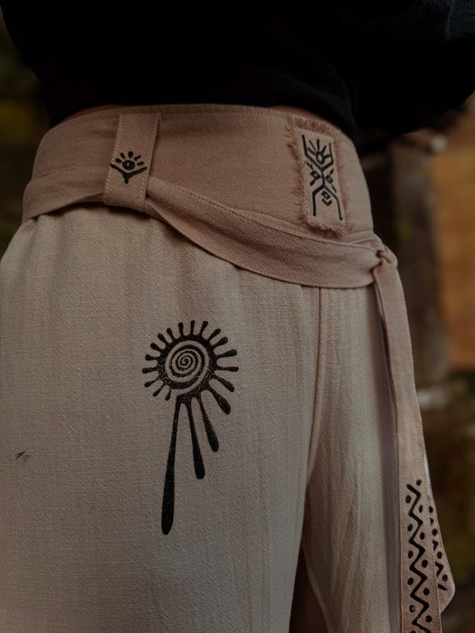 Beige pants with black abstract designs on a blurred natural background