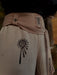 Beige pants with black abstract designs on a blurred natural background