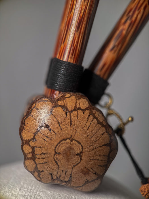 Wooden tool with a textured handle and decorative head on a neutral background