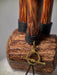 Wooden object with a gold ring and black cord on a textured surface