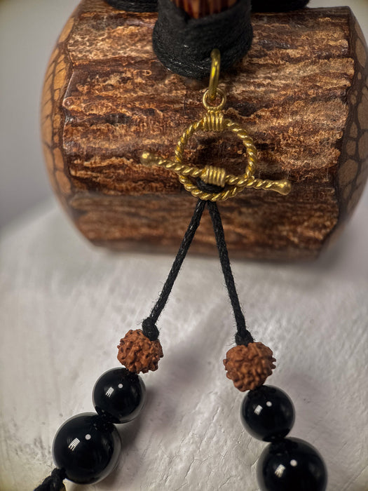 Black beaded necklace with gold clasp on a wooden block