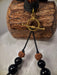 Black beaded necklace with gold clasp on a wooden block
