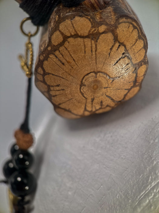 Wooden pendant with intricate carvings on a plain background