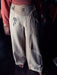 Light-colored pants with tribal designs worn by a person, against a dark background