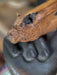 Wooden handle with a carved animal head design held by a dark-colored hand.