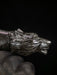 Metallic wolf head figurine held by a gloved hand against a dark background