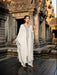 Woman in a white dress standing in front of an ancient temple.
