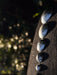 Hammered metal stones arranged on a dark surface with a blurred natural background