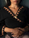 Person wearing a black and brown patterned top with a gold necklace.