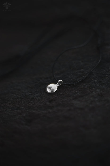 Silver pendant on a dark textured fabric background